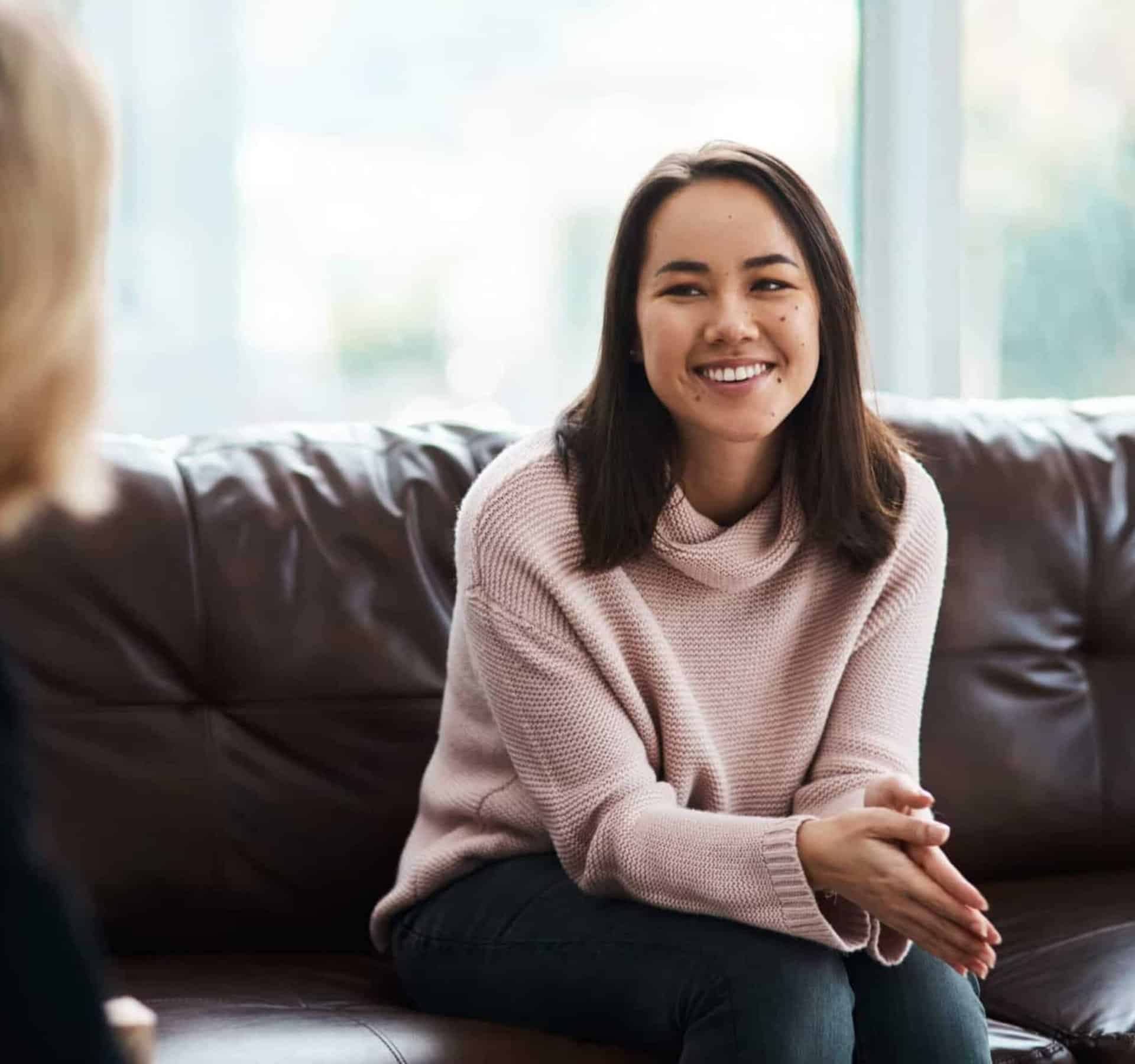 Happy young woman sitting on the couch during inpatient rehab.
